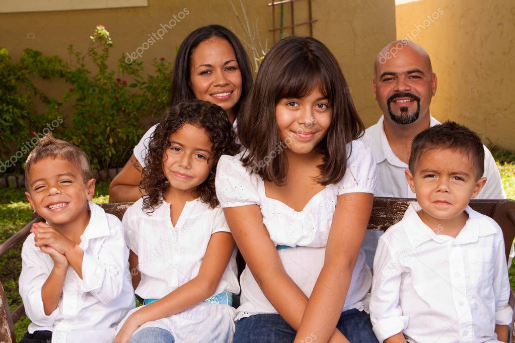 Happy Hispanic family laughing and smiling outside.