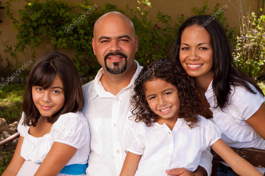 Happy Hispanic family laughing and smiling outside.