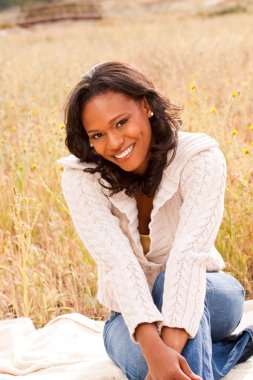 Bir alan gülümseyerek oturan mutlu kadın.