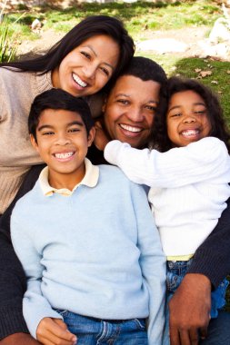 Biracial aile gülüyor ve dışarıda gülümseyen.