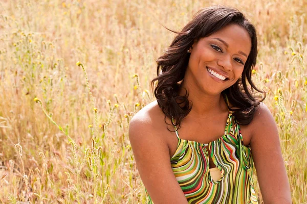 Mujer feliz sentada en un campo sonriendo . — Foto de Stock