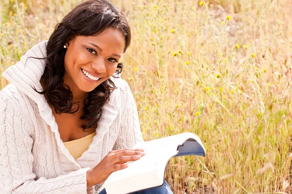 Happy woman sitting outside reading The Bible. — Stock Photo, Image