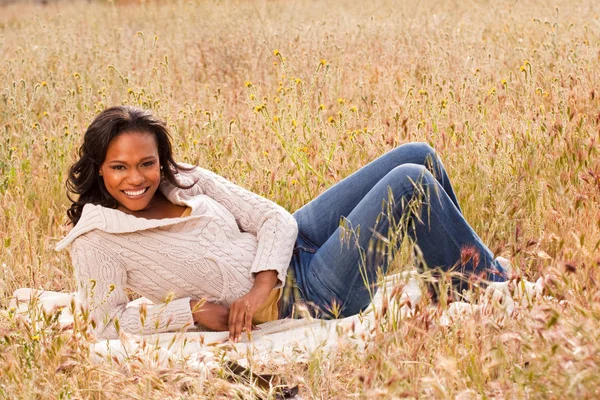 Mujer feliz sentada en un campo sonriendo . — Foto de Stock