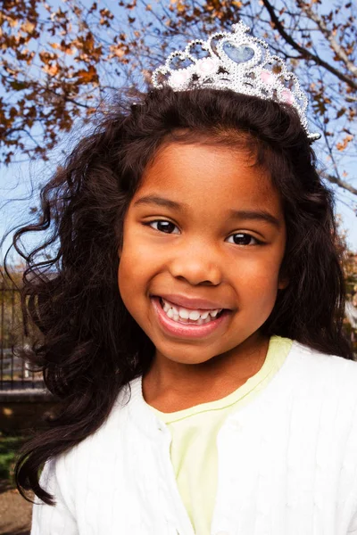 Linda niña sonriendo usando una tiara . — Foto de Stock