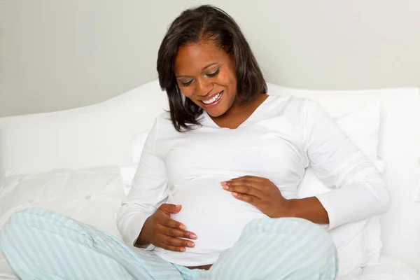 Junge afrikanisch-amerikanische schwangere Frau hält ihren Bauch. — Stockfoto