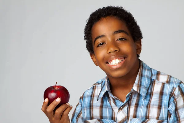 Ung African American kid äta ett äpple som isolerad på vit. — Stockfoto