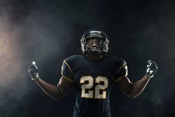 African American football player isolated on black.