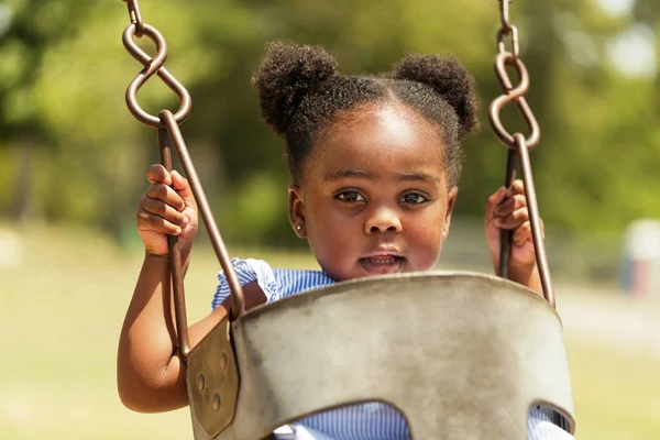 Schattige kleine Afrikaanse Amerikaan swingen in het park. — Stockfoto