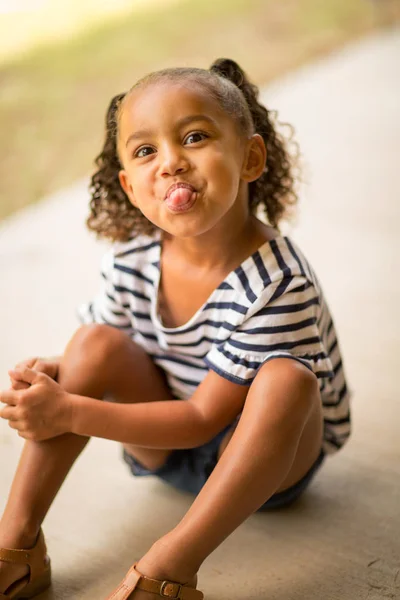 Linda niña de raza mixta riendo y haciendo caras . — Foto de Stock