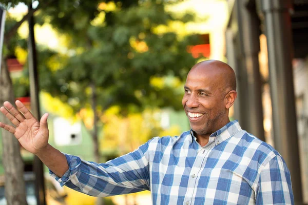 Afrikanischer Amerikaner lächelt und zeigt von der Kamera weg. — Stockfoto