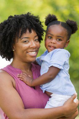Afrika kökenli Amerikalı anne gülerek ve kızını sarılma.