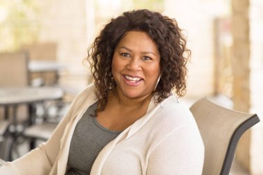 Güzel olgun Afro-Amerikan kadın gülümseyerek ve gülüyor.