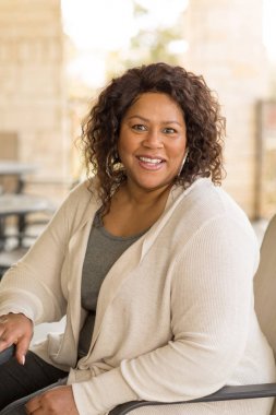 Güzel olgun Afro-Amerikan kadın gülümseyerek ve gülüyor.