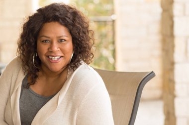 Güzel olgun Afro-Amerikan kadın gülümseyerek ve gülüyor.