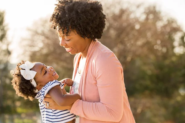 Africká americká matka směje a drží její dcera. Stock Obrázky