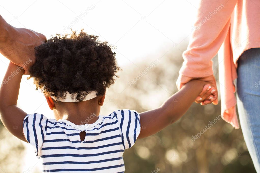 Little girl holding hands with her parents.