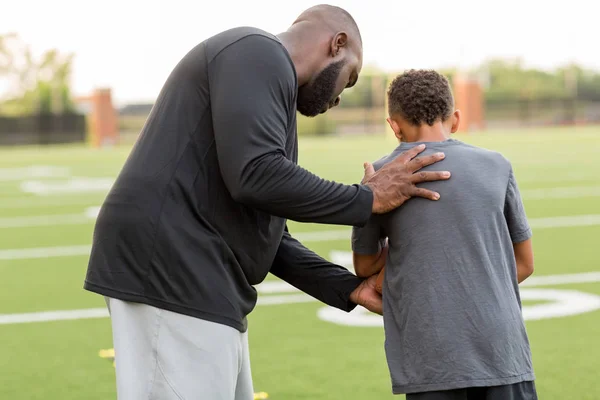 Entraîneur de football américain entraînant un jeune athlète . — Photo