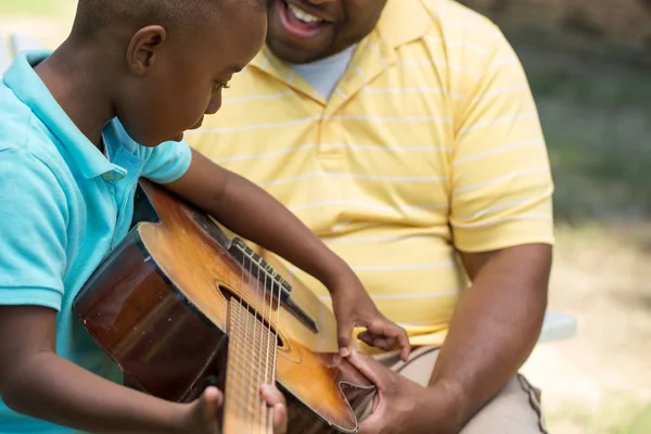 Father teaaching his his son to play the guitar.
