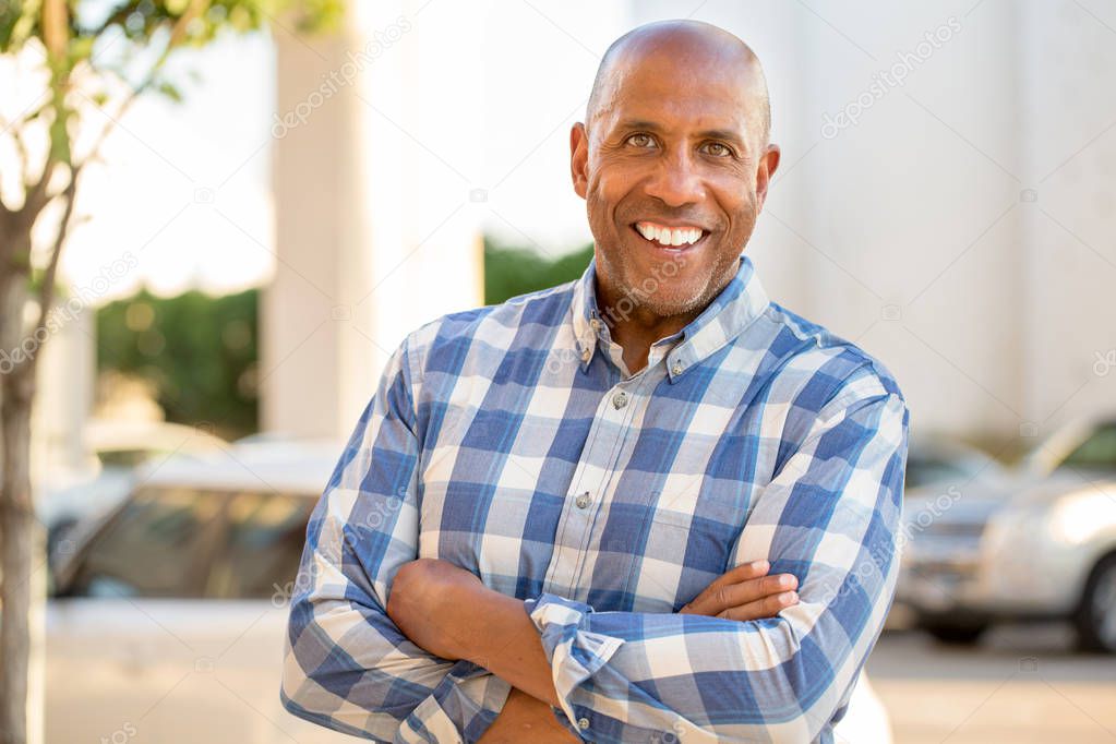 Happy mature African American man smiling outside.