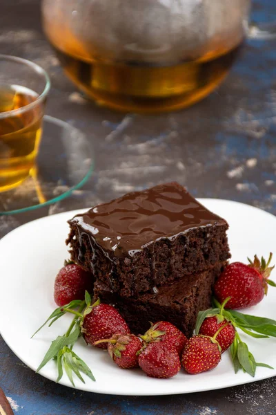 Vegan brownie with chocolate glaze, strawberries and tea