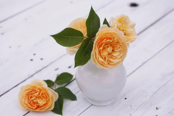 Yellow English Rose in vase on wooden table with petals