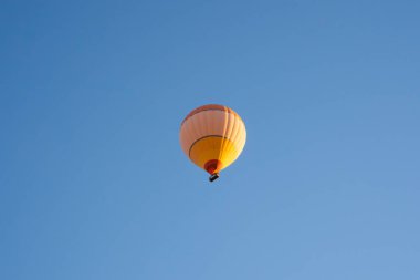 Büyük sarı ve turuncu sıcak hava balonu Greme Ulusal Parkı 'ndaki Aşk Vadisi' nin üzerinden uçtu. Kapadokya, Türkiye.