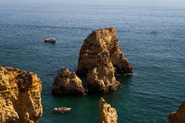 Ponta da Piedade 'nin güzel uçurumları. Kireçtaşı kayasının doğal oluşumu. Ortasında bir tekne var. Lagos, Algarve, Portekiz.