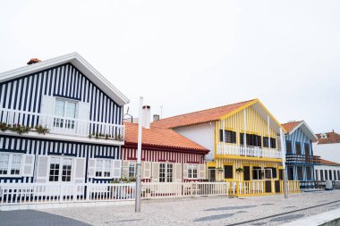 Costa Nova sahilinde renkli çizgili evler. Mavi, sarı ve kırmızı evler. Orijinal tasarım bir balıkçının köyünde. Aveiro, Portekiz.