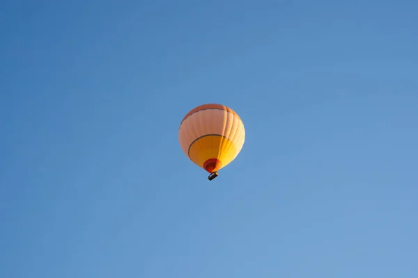 Büyük sarı ve turuncu sıcak hava balonu Greme Ulusal Parkı 'ndaki Aşk Vadisi' nin üzerinden uçtu. Kapadokya, Türkiye.