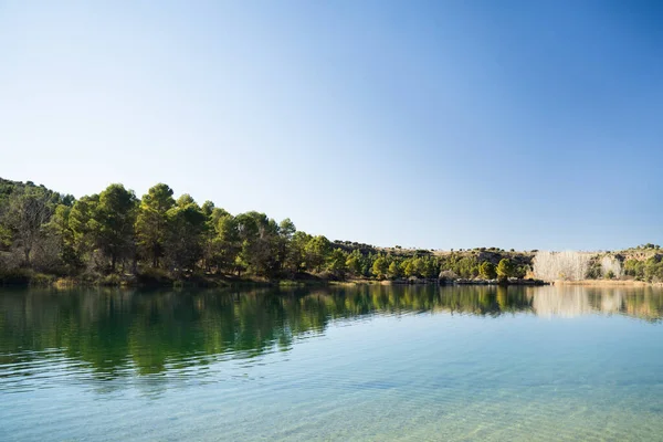 Ossa de Montiel, Albacete, İspanya 'daki' Lagunas de Ruidera 'doğal parkında arka planda ağaçlarla güzel ve sakin bir göl.