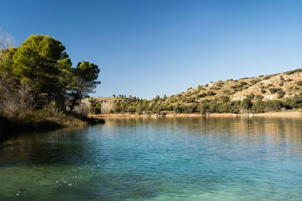 Arkasında ağaçlar ve dağlar olan güzel bir lagün Ossa de Montiel, Albacete, İspanya 'daki' Lagunas de Ruidera 'doğal parkında.