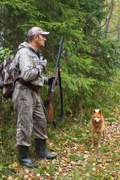hunter with a dog beckons hazel hen on a forest glade