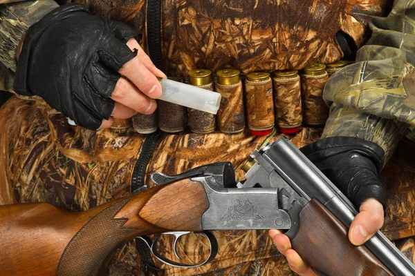 hunter in camouflage pulls out a shell casing from a shotgun, closeup