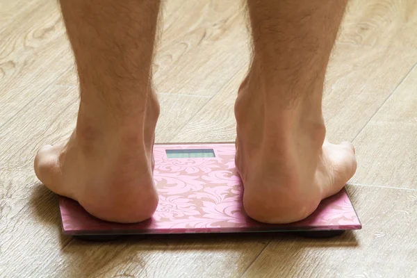 floor scales on which a man measures his weight