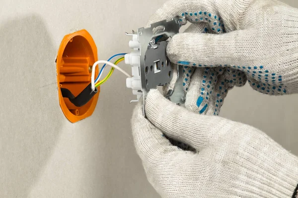 disassembled electrical outlet is in the hands of an electrician