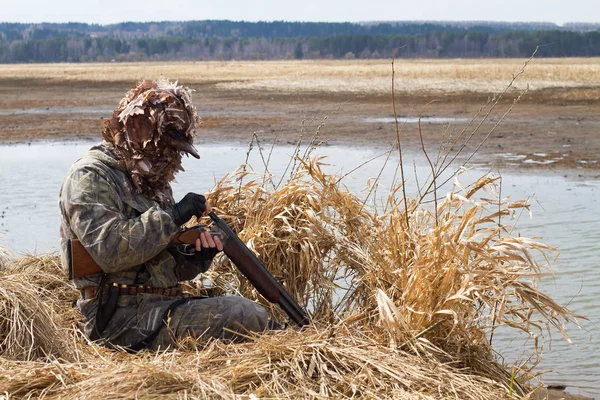 duck hunter charges the shotgun next to the hunting blind