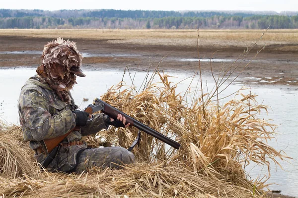 duck hunter charges his shotgun next to the hunting blind