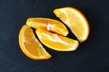 Siyah bir zemin üzerine sulu portakal dilim.