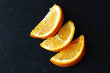 Siyah bir zemin üzerine sulu portakal dilim.