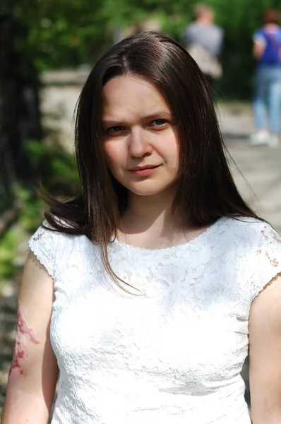 Portrait of a girl in a white blouse in a summer park.