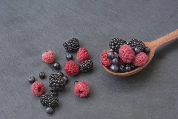 Lot Berries Raspberries Blackberries Blueberries Poured Wooden Spoon Black Background — Stock Photo, Image