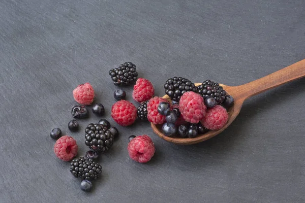 Lot Berries Raspberries Blackberries Blueberries Poured Wooden Spoon Black Background — Stock Photo, Image