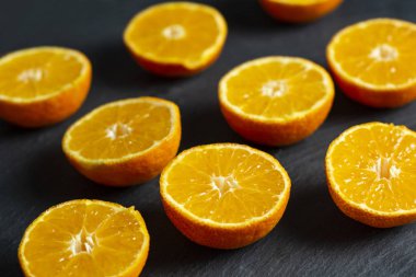 Bir sürü siyah bir zemin üzerine dilimlenmiş mandalina.