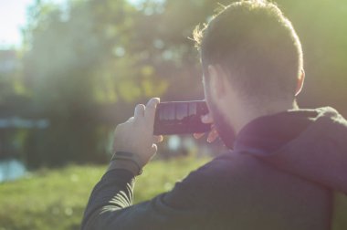 Bir sakallı bir adam gün batımında güzel bir manzara telefonda çekim.