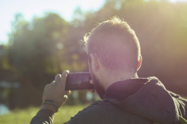 Bir sakallı bir adam gün batımında güzel bir manzara telefonda çekim.