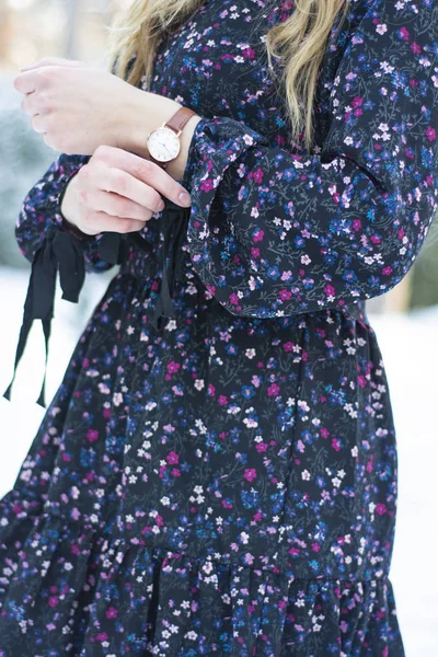 The girl in a beautiful dress looks at her watch.