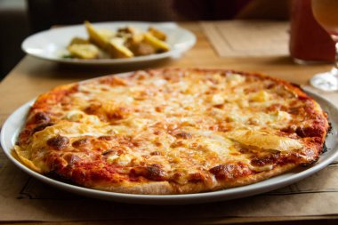 Restoranda masada büyük peynirli pizza.