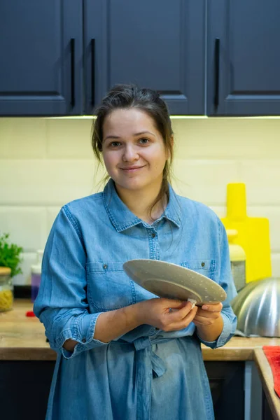 The girl washes the dishes in the kitchen.