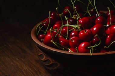 Tahta masadaki bir kasede sulu kirazlar - yan görünüş