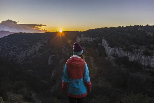 Girl standing on a cliff in mountains at sunset — Stock Photo, Image